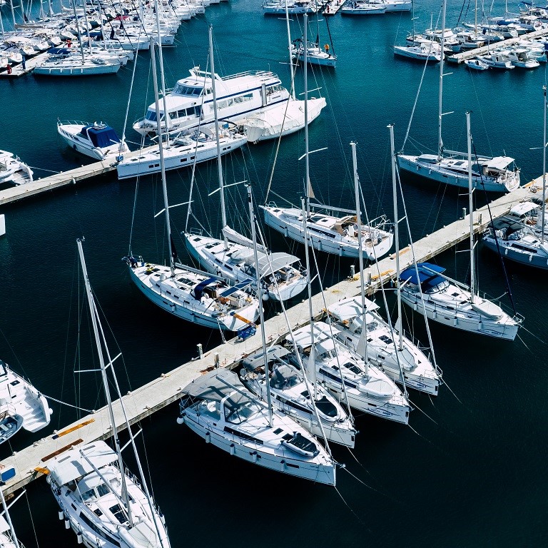 Aerial view of a lot of white boats and yachts moored in marina. Photo made by drone from above.